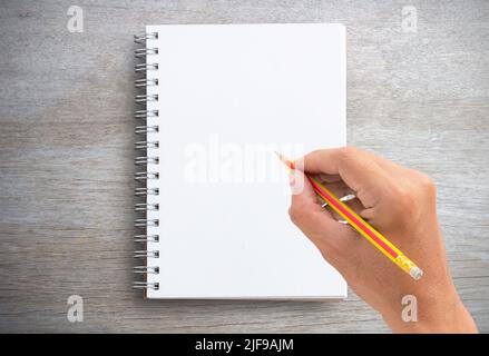Männliche Hand schreibt in einem großen Notizblock auf Holz Platz für die Kopie des Hintergrundtextes der Tabelle Stockfoto