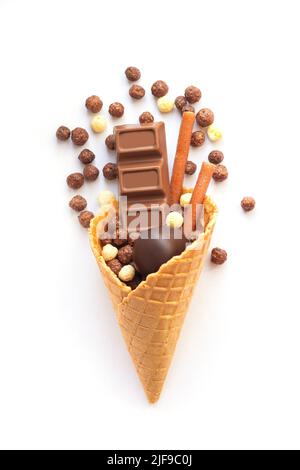 Eiswaffelkegel mit verschiedenen Schokoladenbonbons auf weißem Hintergrund isoliert. Stockfoto