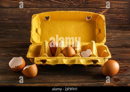 Papphalter mit Hühnereiern und Muscheln auf Holzboden Stockfoto