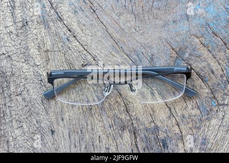 Gläser liegen auf dem dunklen Holztisch. Schwarze Gläser auf Holztisch. Büroarbeitsplatz mit Gläsern auf Holztisch. Stockfoto