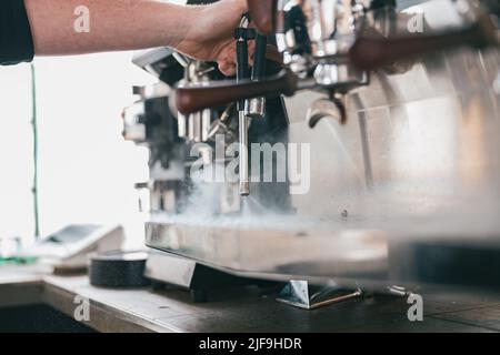 Kaffeemaschine in Dampf, Barista bereitet Kaffee im Café zu Stockfoto