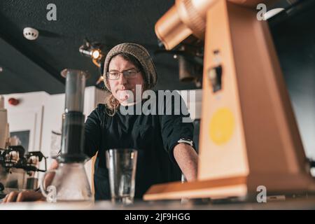 Der Barista macht Kaffee aus Aeropress auf der Holzbar im Café. Alternative Methode zum Brühen von Kaffee Stockfoto