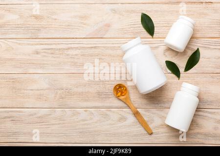 Omega-3 Kapseln liegen in einer weißen Flasche auf einem Tisch mit grünem Blatthintergrund. Fischöltabletten. Biologisch aktive Zusatzstoffe. omega 6, Omega 9, Vitam Stockfoto