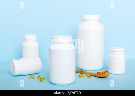 Omega-3 Kapseln liegen in einer weißen Flasche auf einem Tisch mit grünem Blatthintergrund. Fischöltabletten. Biologisch aktive Zusatzstoffe. omega 6, Omega 9, Vitam Stockfoto