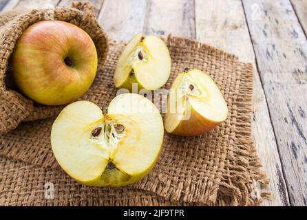 Frische Äpfel im Sackleinen auf einem Holztischhintergrund Stockfoto