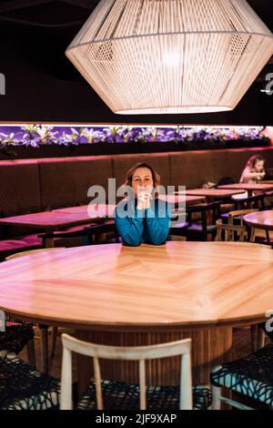 Eine schöne Frau sitzt allein an einem Tisch in einem Restaurant Stockfoto