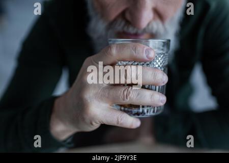 Beschnittene Ansicht eines älteren Mannes, der Whiskey trinkt, während er Glas hält Stockfoto