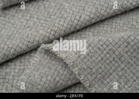 Strukturierter Stoffhintergrund. Eine graue Wolldecke in Falten. Stockfoto