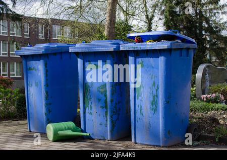 Gruppe von drei großen blauen Mülltonnen auf einem Friedhof in deutschland Stockfoto