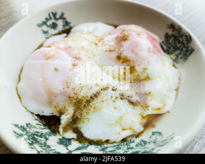 Nahaufnahme von zwei halbgekochten Eiern, serviert mit Sojasauce und weißem Pfeffer. Stockfoto