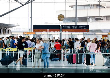 30. Juni 2022, Nordrhein-Westfalen, Köln/Bonn: Flugreisende warten in langen Warteschlangen vor den Check-in-Schaltern am Flughafen Köln/Bonn. Der Flughafen Köln/Bonn hatte bereits vor langen Wartezeiten vor Sicherheitskontrollen gewarnt. Reisende sollten sich mindestens 2,5 Stunden vor Abflug am Flughafen befinden. Foto: Thomas Banneyer/dpa Stockfoto