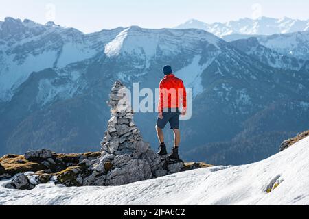 Bergsteiger neben einer Kairon, vor verschneiten Bergen des Rofan, Wanderweg zum Guffert mit Erstschnee, im Herbst Brandenberger Alpen Stockfoto