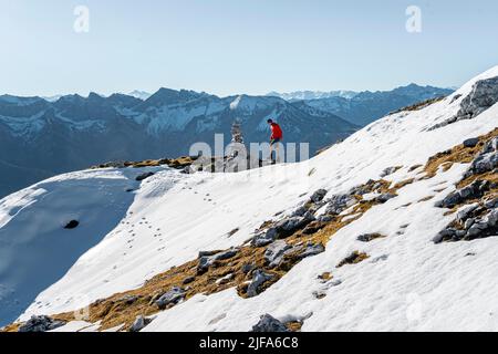 Bergsteiger neben einer Kairon, vor verschneiten Bergen des Rofan, Wanderweg zum Guffert mit Erstschnee, im Herbst Brandenberger Alpen Stockfoto