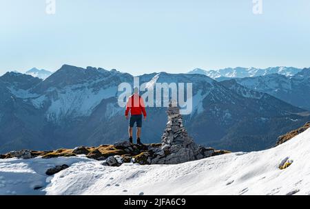 Bergsteiger neben einer Kairon, vor verschneiten Bergen des Rofan, Wanderweg zum Guffert mit Erstschnee, im Herbst Brandenberger Alpen Stockfoto