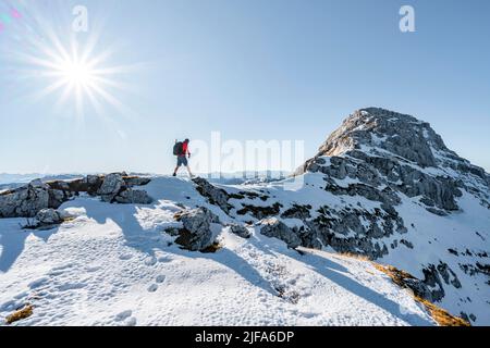 Bergsteiger auf dem felsigen Gipfelgrat mit Herbstschnee, Wanderweg nach Guffert, Sonnenreflex, Brandenberger Alpen, Tirol, Österreich Stockfoto