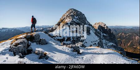 Bergsteiger auf dem felsigen Gipfelgrat mit Herbstschnee, Wanderweg nach Guffert, Sonnenreflex, Brandenberger Alpen, Tirol, Österreich Stockfoto