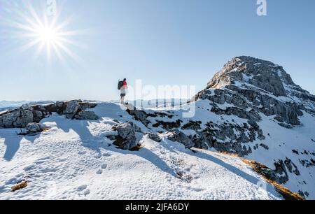 Bergsteiger auf dem felsigen Gipfelgrat mit Herbstschnee, Wanderweg nach Guffert, Sonnenreflex, Brandenberger Alpen, Tirol, Österreich Stockfoto