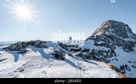 Bergsteiger auf dem felsigen Gipfelgrat mit Herbstschnee, Wanderweg nach Guffert, Sonnenreflex, Brandenberger Alpen, Tirol, Österreich Stockfoto