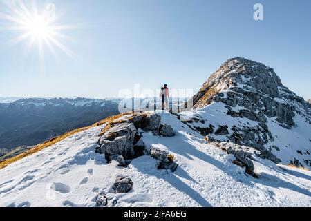 Bergsteiger auf dem felsigen Gipfelgrat mit Herbstschnee, Wanderweg nach Guffert, Sonnenreflex, Brandenberger Alpen, Tirol, Österreich Stockfoto