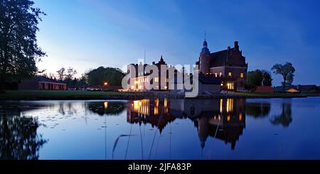 Beleuchtete Burg, die sich in einem ruhigen Gewässer spiegelt, Broholm Slot, Fünen, Dänemark Stockfoto