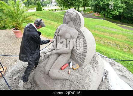 Ludwigsburg, Deutschland. 01.. Juli 2022. Der irische Künstler Fergus Mulvany modelliert eine Sandskulptur einer kleinen Meerjungfrau beim Sandskulptur-Festival im Blühende Barock. In diesem Jahr werden Figuren aus Sand zum Thema „Reise durch Europa“ ausgestellt. Quelle: Bernd Weißbrod/dpa/Alamy Live News Stockfoto