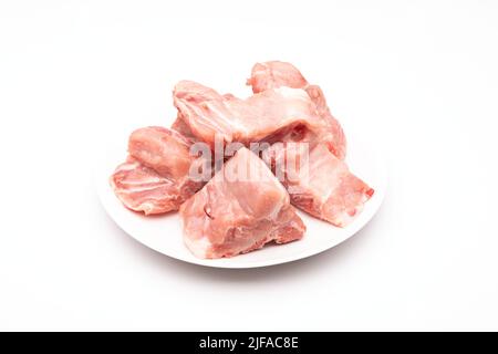Rohe Schweinebone Wirbelsäule in weißer Schale isoliert auf weißem Hintergrund Stockfoto