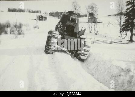 Das Fahrerhaus im Tank der Marke Renault auf einer winterlichen Landstraße. Im Hintergrund eine Reihe von Holzgebäuden. Stockfoto