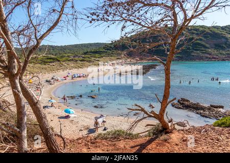 Menorca, Spanien - 30. Jun 2022: Menschen, die in den transparenten Gewässern der unberührten Bucht Algaiarens auf Menorca baden Stockfoto