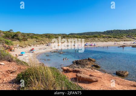 Menorca, Spanien - 30. Jun 2022: Menschen, die in den transparenten Gewässern der unberührten Bucht Algaiarens auf Menorca baden Stockfoto