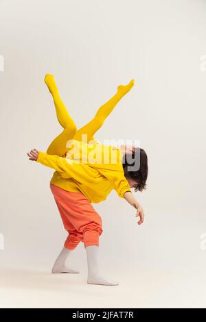 Portrait von jungen Mann und Frau in bunten Outfit Spaß haben, tanzen, posieren isoliert über grauen Studio-Hintergrund Stockfoto