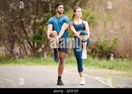 Fit jungen Mann und Frau Stretching Beine für Aufwärmen, um Verletzungen zu vermeiden, während gemeinsam trainieren im Freien. Interracial paar und motivierte Athleten Stockfoto