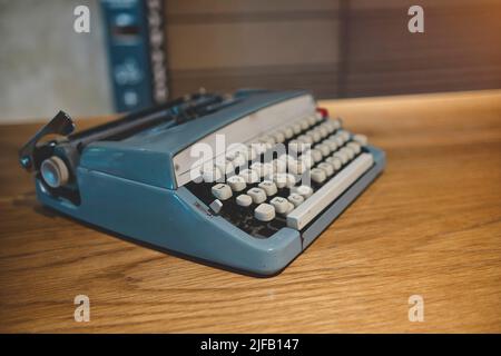 Retro alte Schreibmaschine auf verwackelte Hintergrund und vor Holztisch. Vintage-Konzept, selektiver Fokus. Stockfoto