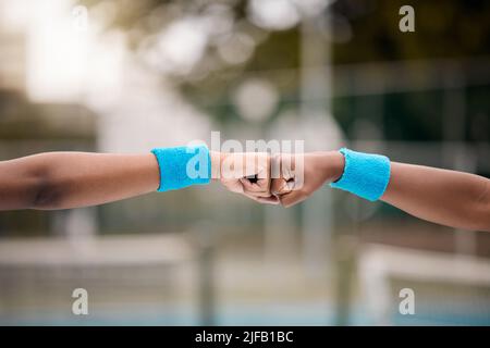 Nahaufnahme der Hände der Tennisspieler auf dem Platz. Zwei Tennisspieler geben sich einen Fauststoß. Freunde motivieren sich gegenseitig auf dem Tennisplatz Stockfoto