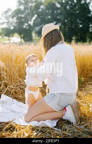 Mama wechselt im Urlaub in der Natur die Kleidung des Kindes Stockfoto