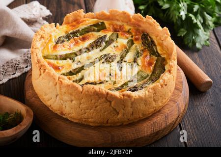 Quiche. Hausgemachter Spargelkuchen oder Quiche mit Käse und Spinat auf altem dunklen Holztisch Hintergrund. Draufsicht. Stockfoto