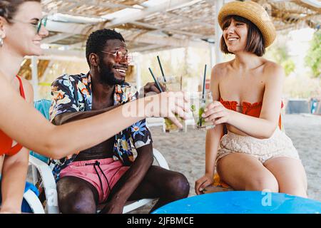 Die besten multiethnischen Freunde im Urlaub haben Spaß beim Toasten mit frischen tropischen Mojito-Cocktails zusammen im Beach Pub Bar Restaurant - Menschen Freundschaft Stockfoto