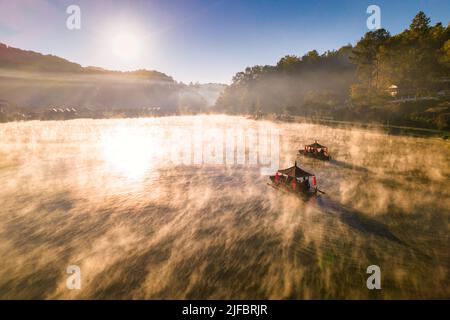 Luftaufnahme eines chinesischen Ruderbootes im Morgengrauen mit Nebel über dem Ban Rak Thai Lake, Thailand Stockfoto