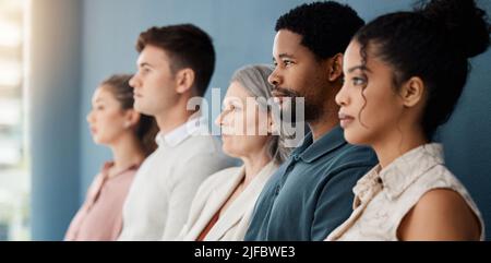 Eine Gruppe seriöser Geschäftsleute, die in einem Büro in einer Reihe sitzen. Gesichter von Geschäftsleuten, die in einem Warteraum zusammen in einem sitzen Stockfoto