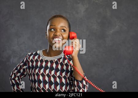 Lächelnde ethnische Frau spricht am Telefon mit dem Kunden Stockfoto