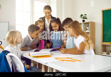 Eine Gruppe glücklicher Schulkinder mit ihrem Lehrer, der Unterricht im Klassenzimmer hat Stockfoto