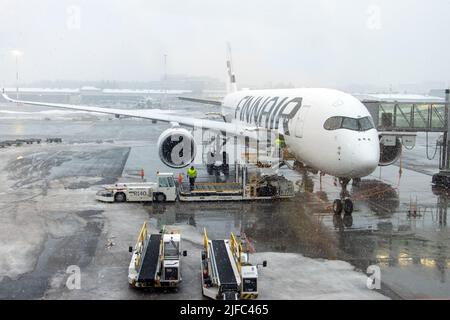 HELSINKI, FNLAND, 15 2022. FEBRUAR, Schnee fällt auf den Flughafen, auf den das Flugzeug vor dem Start verladen wird, Helsinki Airport, Finnland. Stockfoto