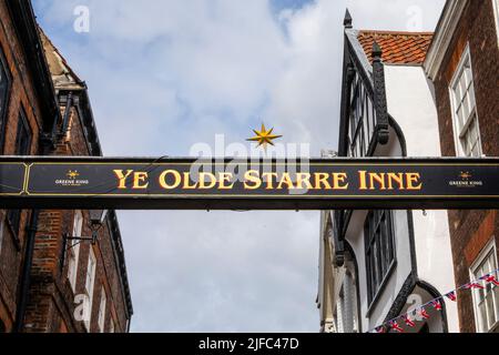 York, Großbritannien - 6. 2022. Juni: Ein Schild über der Straße auf Stonegate in York, Großbritannien, das den Standort des öffentlichen Hauses Ye Olde Starre inne markiert. Stockfoto