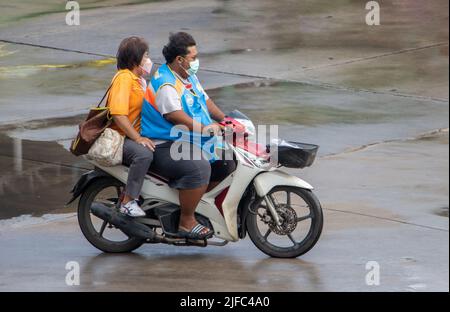 SAMUT PRAKAN, THAILAND, 28 2022. MÄRZ, Ein Taxifahrer auf einem Motorrad fährt mit einer Frau auf einer nassen Straße. Stockfoto