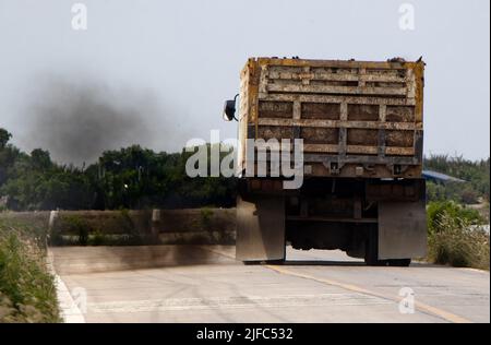 Ein beladener LKW fährt mit dickem schwarzen Rauch vom Auspuff auf die Straße Stockfoto