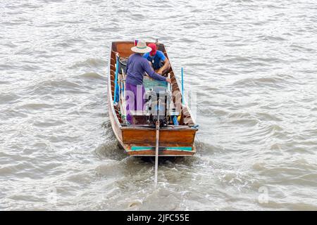 Asiatische Fischer segeln auf einem Boot und werfen ihre Netze ins Wasser Stockfoto