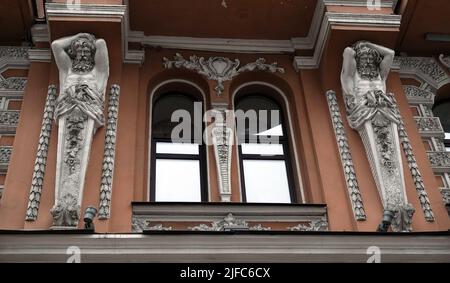 Kiew, Ukraine 28. November 2020: Künstlerische Dekoration der Fassade des Gebäudes mit Skulpturen und Büsten von Atlanten in der Stadt Kiew Stockfoto