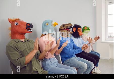 Diverse Mitarbeiter in Tierkopfmasken applaudieren Stockfoto