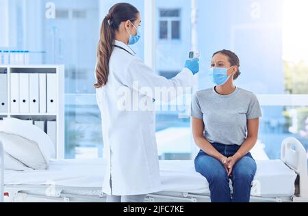 Die Patientin muss ihre Temperatur mit einem Thermometer überprüfen lassen. Arzt, der die Temperatur eines Patienten mit einem Thermometer misst. Patient in Rücksprache mit dem Arzt Stockfoto