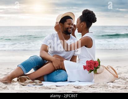Fröhliches afroamerikanisches Paar, das zusammen einen Tag am Meer verbringt. Content Freund und Freundin starren einander liebevoll in die Augen während Stockfoto