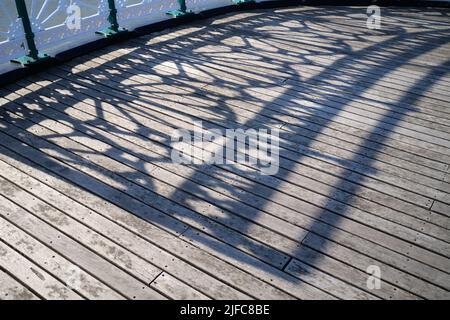 Schatten, die von der Iron Railings entlang des viktorianischen Pier Penarth, South Wales, Großbritannien, reflektiert werden Stockfoto